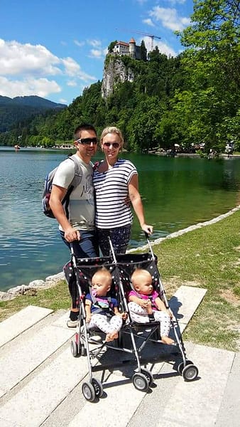 A family posing outside on a sunny day at Lake Bled Slovenia, pushing a travel stroller double