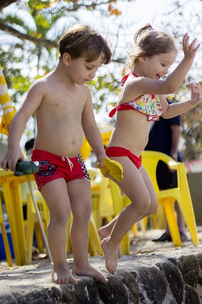 Boy Girl Twins jumping into the water at the beach