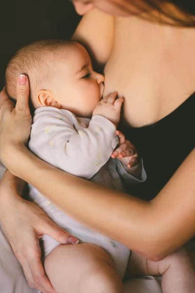 A mother, cradling her breastfeeding baby, sharing an intimate moment together.