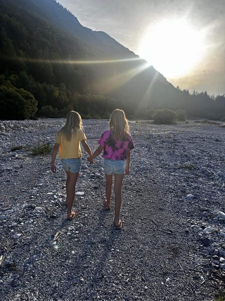 twin bond, mirror twins, twins holding hands and walking down a river bed.