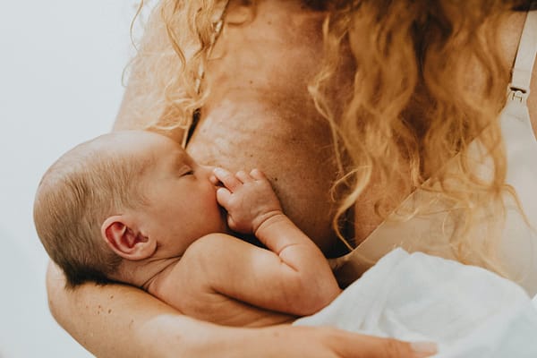 A mother, with long hair, breastfeeding her beautiful newborn baby