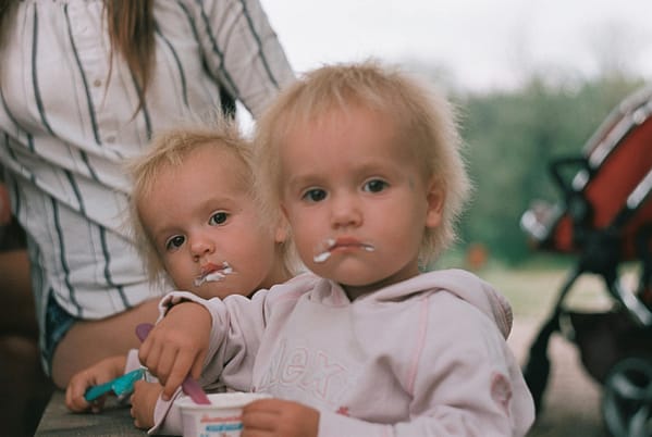 Identical twin boys eating yoghurt with their mom