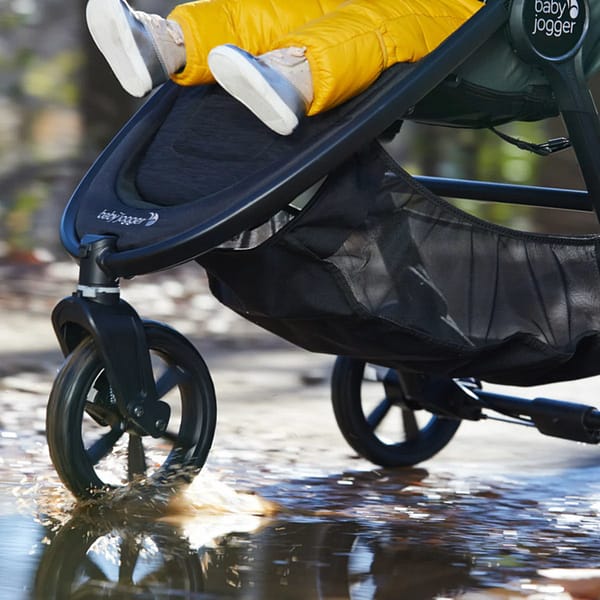 A baby in a pram, rolling through a puddle outside on a winter day